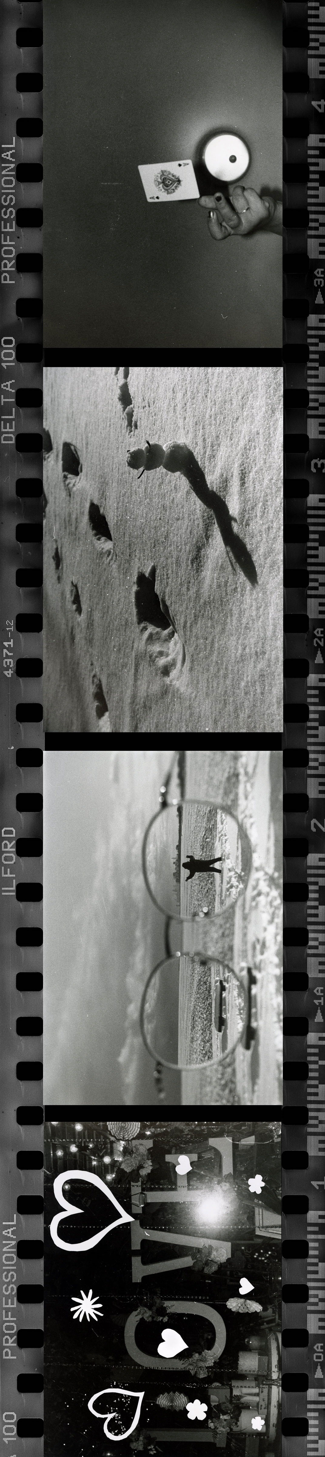 A film roll of black and white photos taken by Joy: a hand holding a playing card, a small snowman in the snow, a pair of glasses through which a standing person is seen and a sign that says 'LOVE' with hearts surrounding it.
